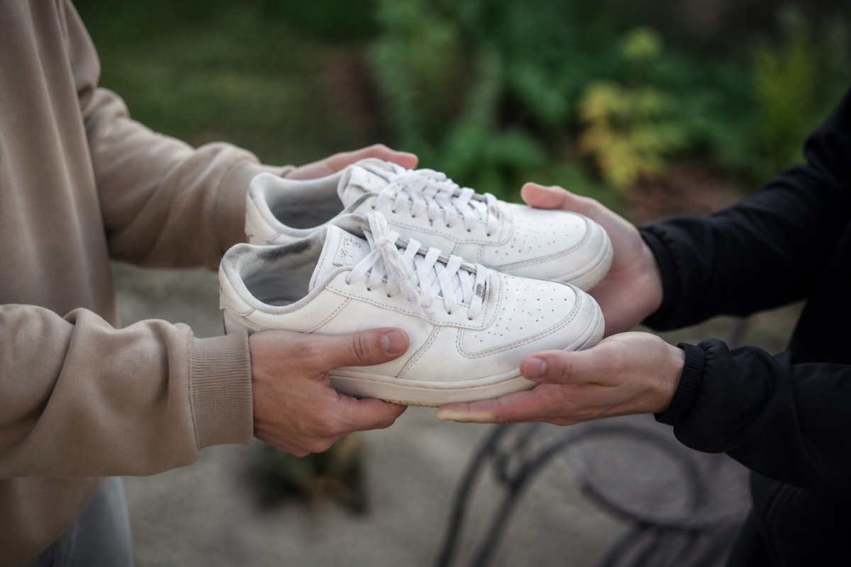 Chaussures blanches echangees entre deux paires de mains