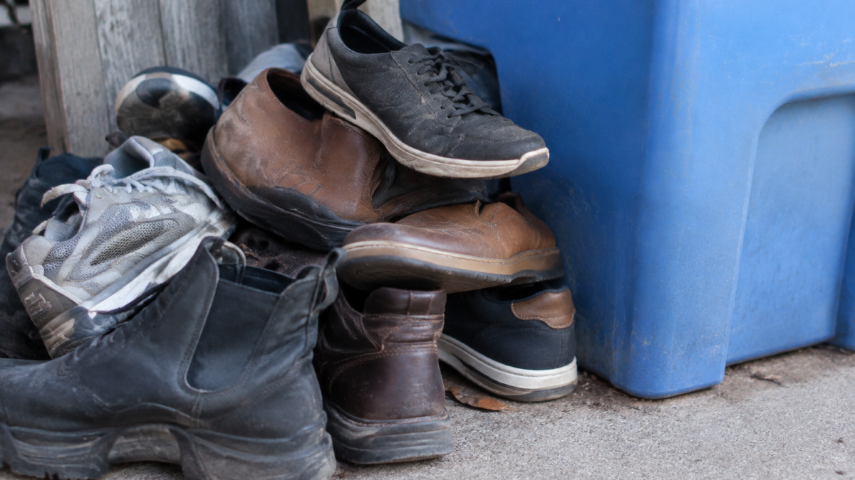 Pile de vieilles chaussures empilees aupres d'un bac bleu