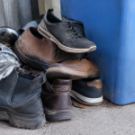 Pile de vieilles chaussures empilees aupres d'un bac bleu