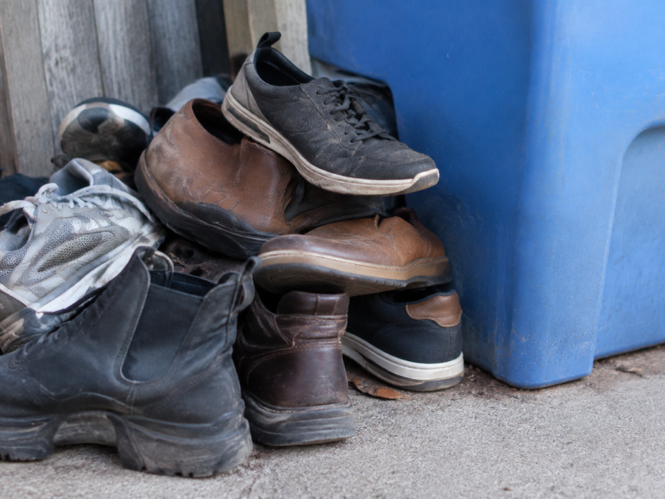 Pile de vieilles chaussures empilees aupres d'un bac bleu